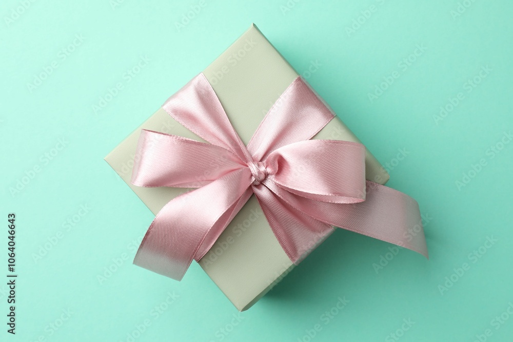 Gift box with bow on turquoise background, top view Gift box with bow on turquoise background, top view