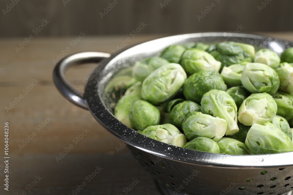 Fresh Brussels sprouts in metal colander on wooden table, closeup Fresh Brussels sprouts in metal colander on wooden table, closeup