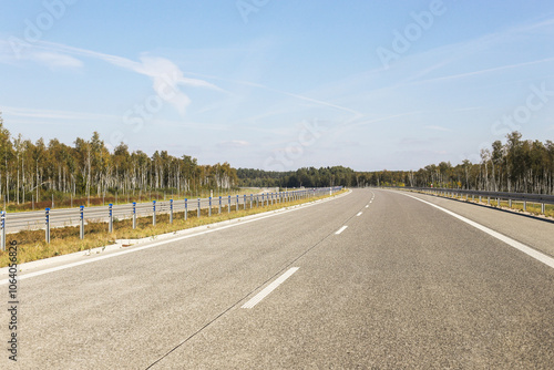 Multiband highway empty road. Driving under a bright blue sky. Overpass and roadside view on a clear day in Europe. Asphalt road landscape. Traveling thought the country background. photo