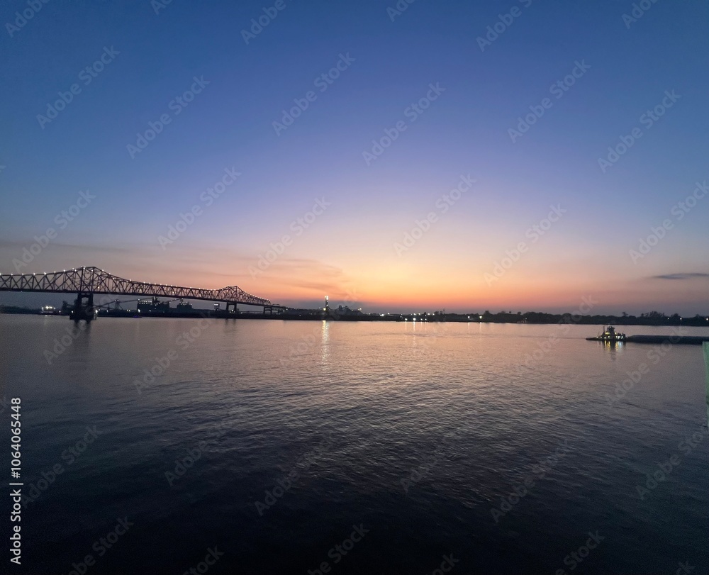 Obraz premium Sunset on the Mississippi River with tug boat and golden glowing clouds on the blue sky in Baton Rouge, Louisiana, USA