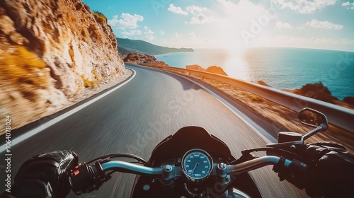 A motorcycle rider drives along a winding coastal road with a stunning sunset in the background.