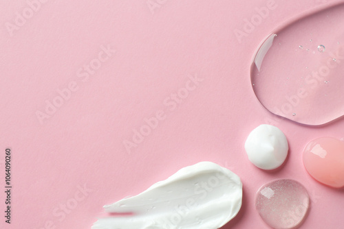 Smears of different cosmetic products on pink background, flat lay. Space for text