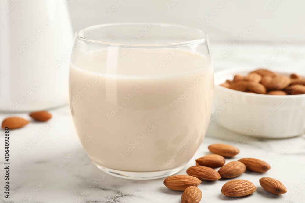 Glass of almond milk and nuts on white marble table, closeup Glass of almond milk and nuts on white marble table, closeup