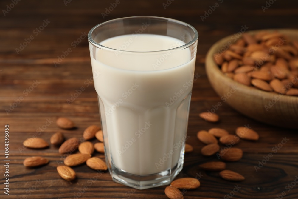 Fresh almond milk in glass and nuts on wooden table, closeup Fresh almond milk in glass and nuts on wooden table, closeup
