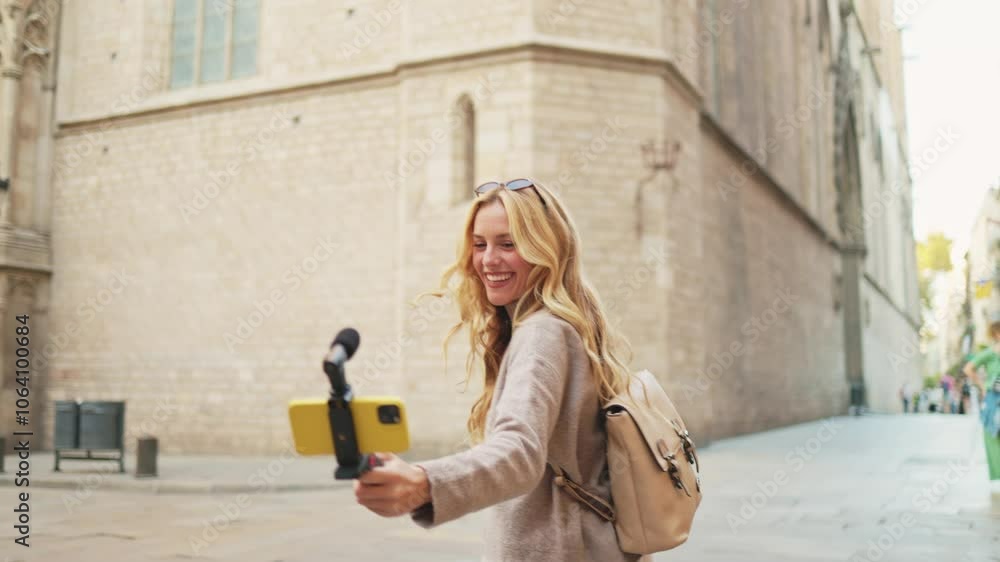 Young woman vlogging in barcelona while using a smartphone gimbal for capturing her travel adventures. Influencer recording video content walking in barcelona Young woman vlogging in barcelona while using a smartphone gimbal for capturing her travel adventures. Influencer recording video content walking in barcelona