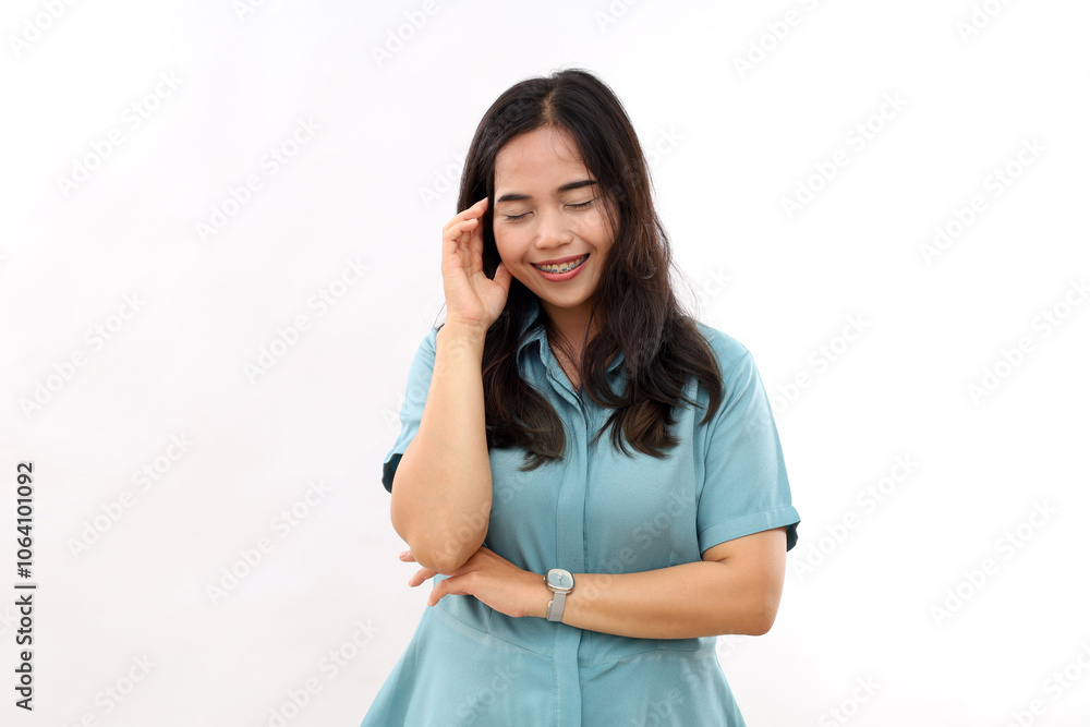 Beautiful happy sincere Asian woman with smooth healthy skin smiles happily keeps eyes closed being in good mood wears casual shirt isolated over white background smiles carefree touches face gently Beautiful happy sincere Asian woman with smooth healthy skin smiles happily keeps eyes closed being in good mood wears casual shirt isolated over white background smiles carefree touches face gently