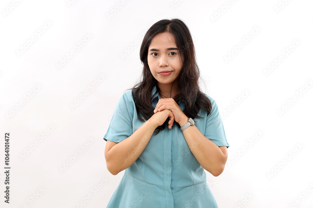 Hopeful good looking young Asian woman keeps hands together in pray gesture has pity expression asks for apology looks with big hope at camera wears shirt poses against bright white background Hopeful good looking young Asian woman keeps hands together in pray gesture has pity expression asks for apology looks with big hope at camera wears shirt poses against bright white background