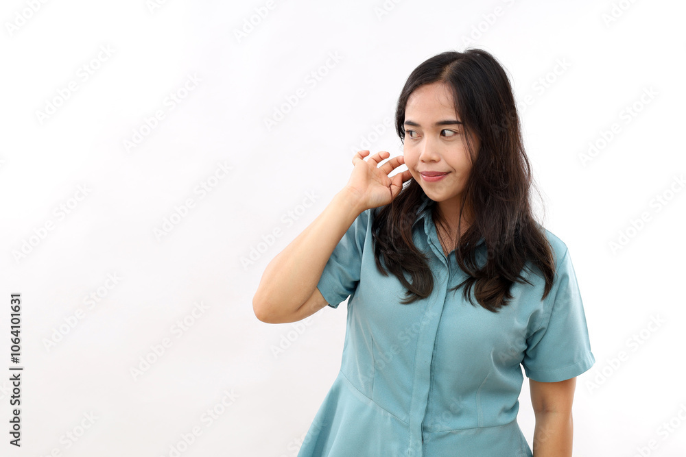 Indoor shot of pleasant looking young Asian woman keeps hand on hair focused away thinks about something wears shirt isolated over white background copy space for your advertising content Indoor shot of pleasant looking young Asian woman keeps hand on hair focused away thinks about something wears shirt isolated over white background copy space for your advertising content