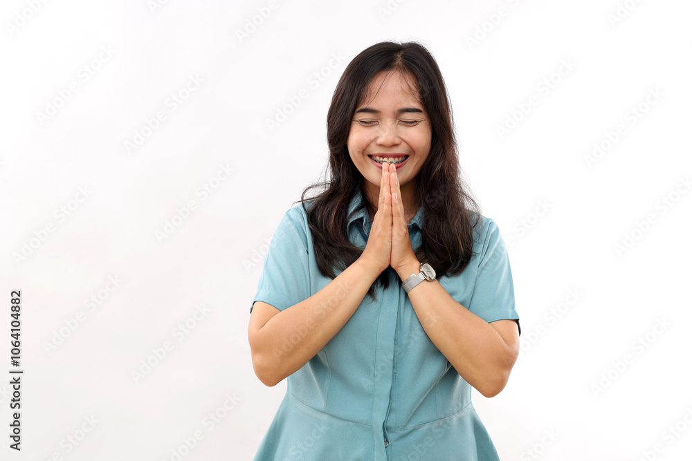 Smiling young girl enjoys keeps palms together and laughs happily with closed eyes being amused dressed casual shirt isolated on white background. Positive emotions concept