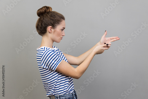 Side view of assertive dangerous woman pointing fingers at target imitating weapon making shot.