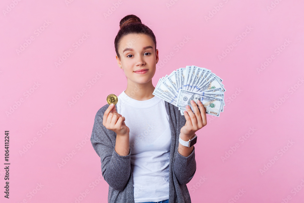 Confident teenage girl in casual clothes standing showing dollar banknotes and golden bitcoin. Confident teenage girl in casual clothes standing showing dollar banknotes and golden bitcoin.