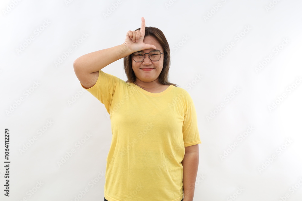 Smiling Asian girl makes loser gesture over forehead, lost shape L ...