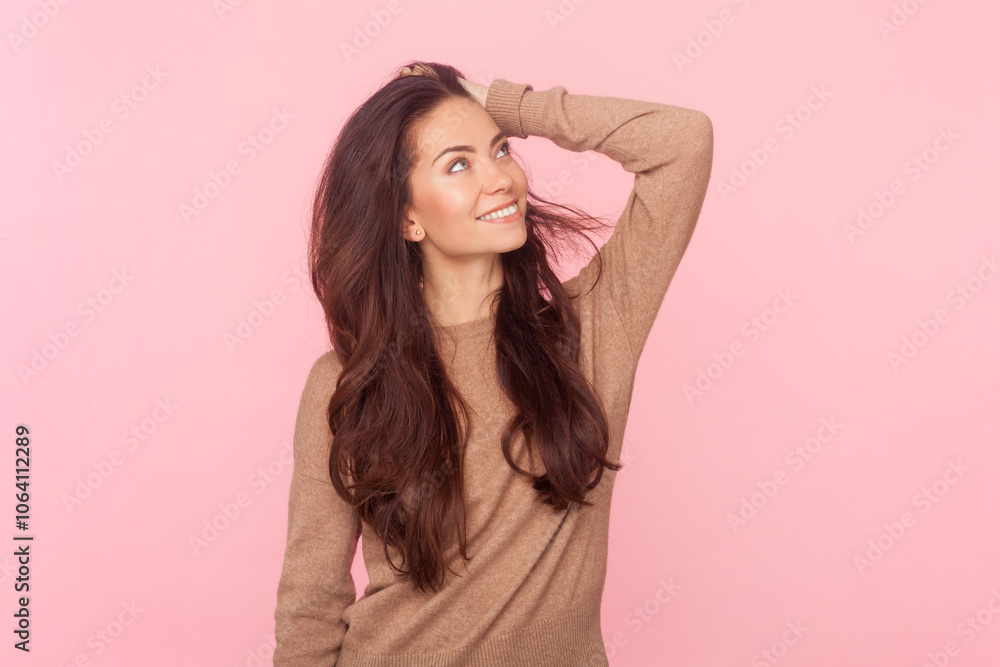 Attractive dreaming smiling woman with wavy hair, keeps hand on her head, looking away Attractive dreaming smiling woman with wavy hair, keeps hand on her head, looking away