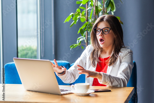 Shocked scared woman working on laptop sees something frighten on notebook display screaming fear.