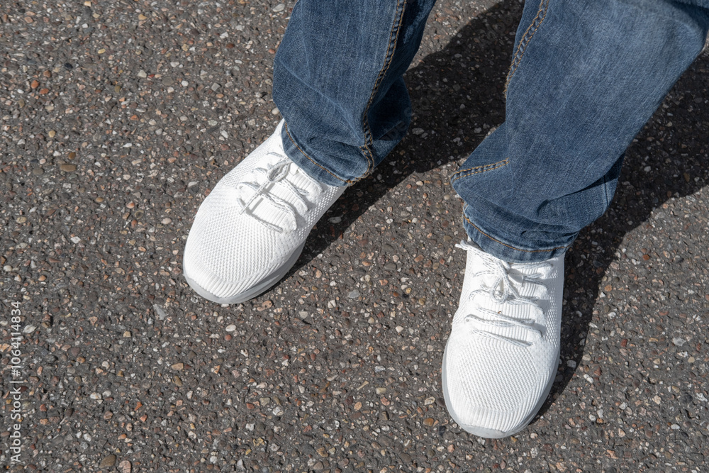 close-up shot featuring stylish pair of white sneakers adorned by man's legs in denim jeans, trendy casual fashion concept, showcasing modern style and youthful vibe person close-up shot featuring stylish pair of white sneakers adorned by man's legs in denim jeans, trendy casual fashion concept, showcasing modern style and youthful vibe person