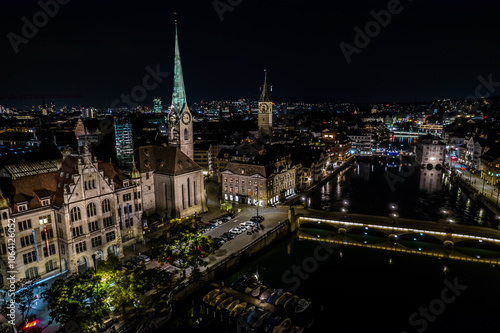 Beautiful aerial view of the city of Zurich in Switzerland at night - the Limmat River and its iconic churches, buildings rivers and Clocks.