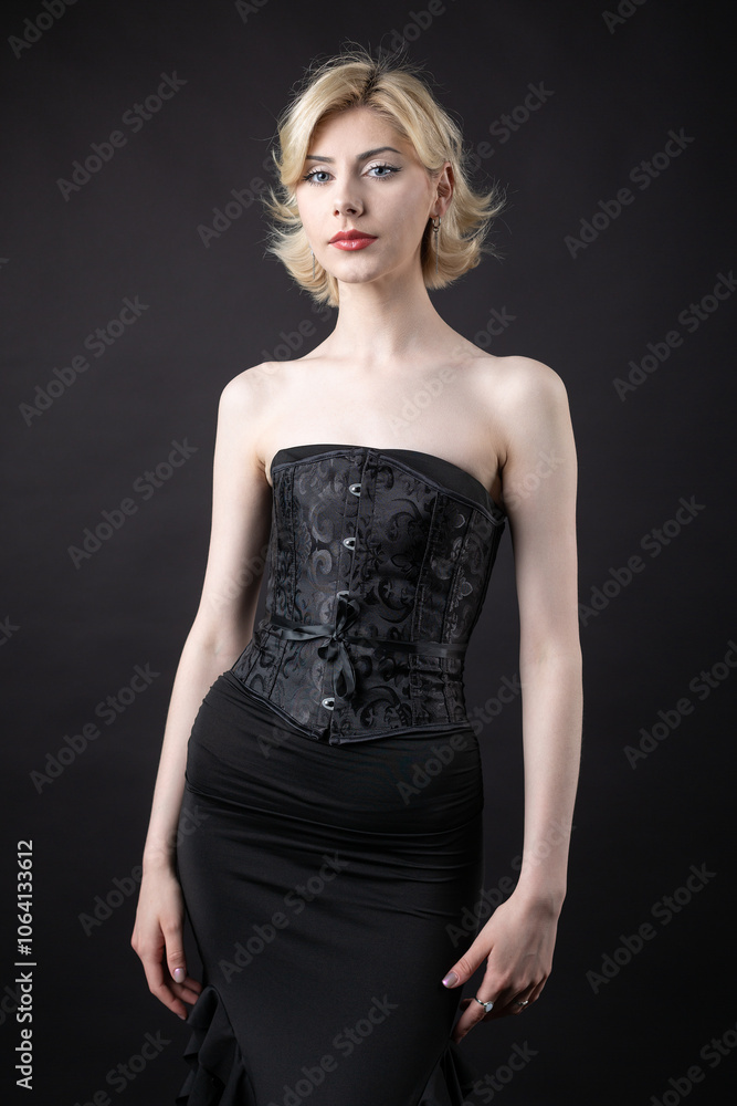Expressive young blonde under a bob in the studio. In a black corset and dress. Expressive young blonde under a bob in the studio. In a black corset and dress.
