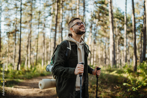 Young caucasian man hiking or trekking through the forest 