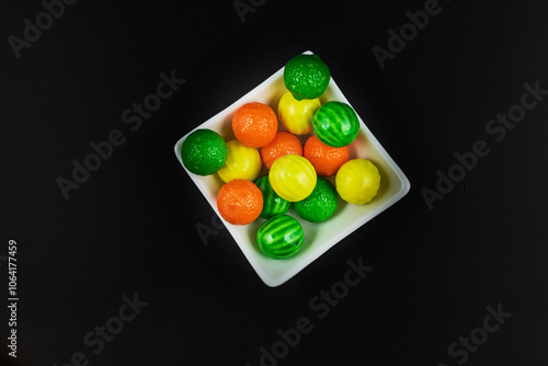 Chewing gum balls of different colors in shiny earthenware containers with a homogeneous colored background for placing text