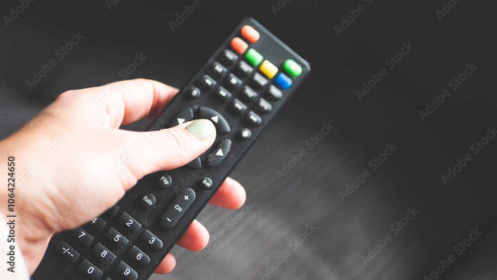 A hand holding remote control fingers black buttons tv A hand holding remote control fingers black buttons tv