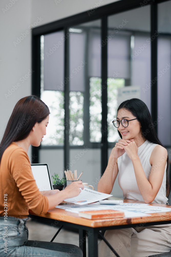 Two women discussing business strategies in a contemporary office setting, showcasing teamwork and collaboration. Two women discussing business strategies in a contemporary office setting, showcasing teamwork and collaboration.