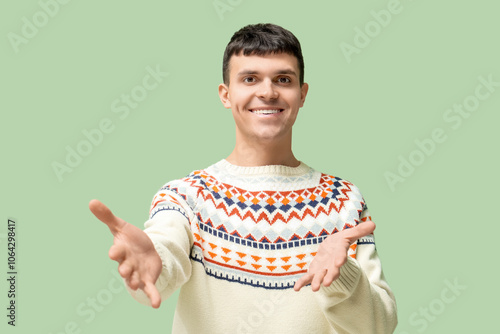 Young deaf mute man using sign language on green background photo