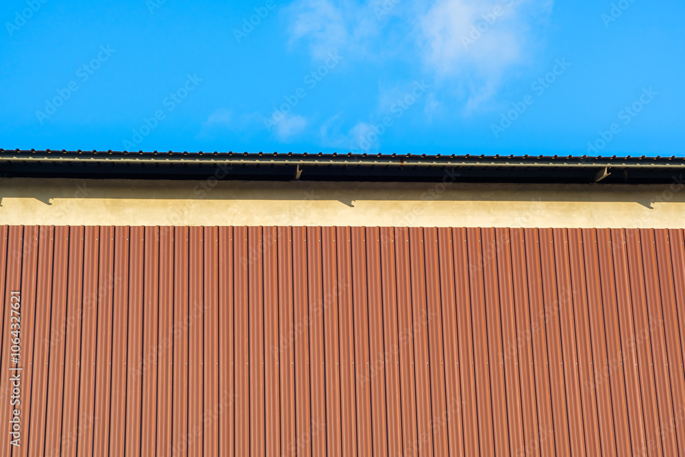 Brown metal sheet walls are attached to the concrete walls of a large factory. Brown metal sheet walls are attached to the concrete walls of a large factory.