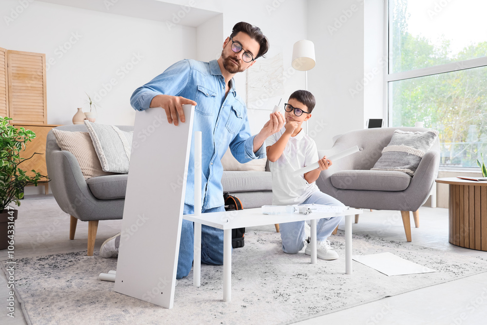 Father with his thoughtful little son assembling shelf unit at home Father with his thoughtful little son assembling shelf unit at home