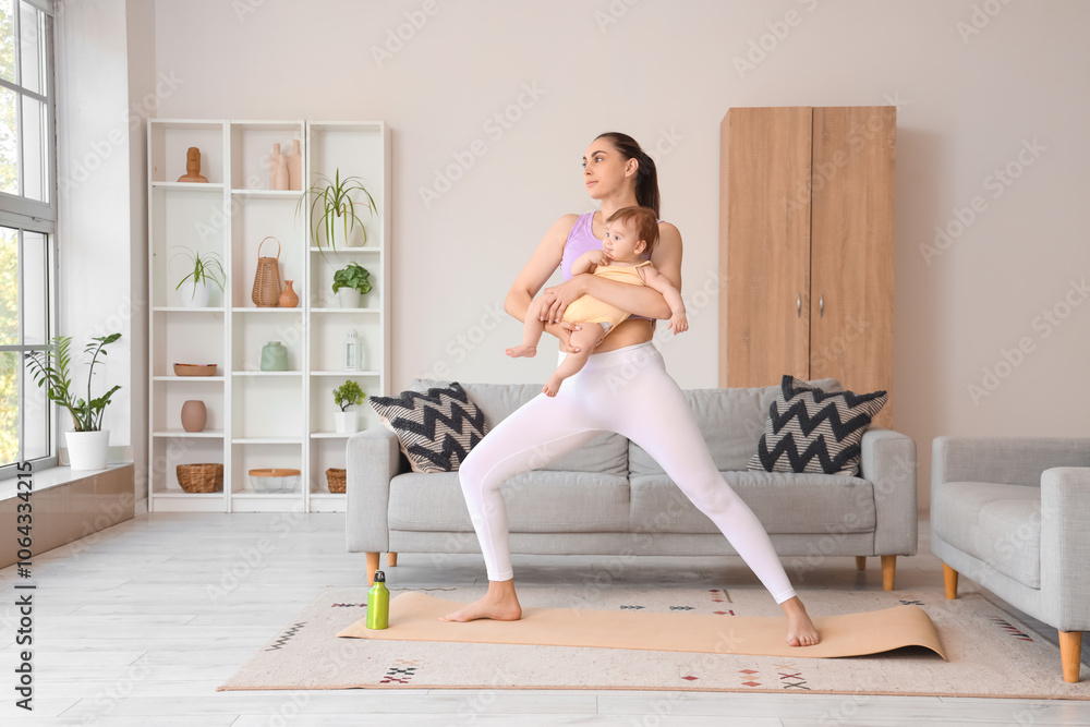 Fototapeta premium Sporty young woman with her little baby doing yoga at home