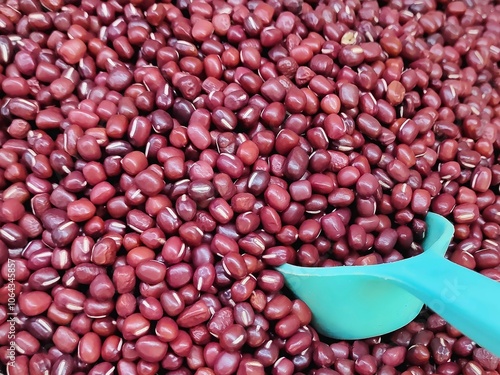 A close-up view reveals vibrant red beans nestled together with a white scope, their glossy surfaces reflecting light and hinting at the delicious dish they will soon become. 