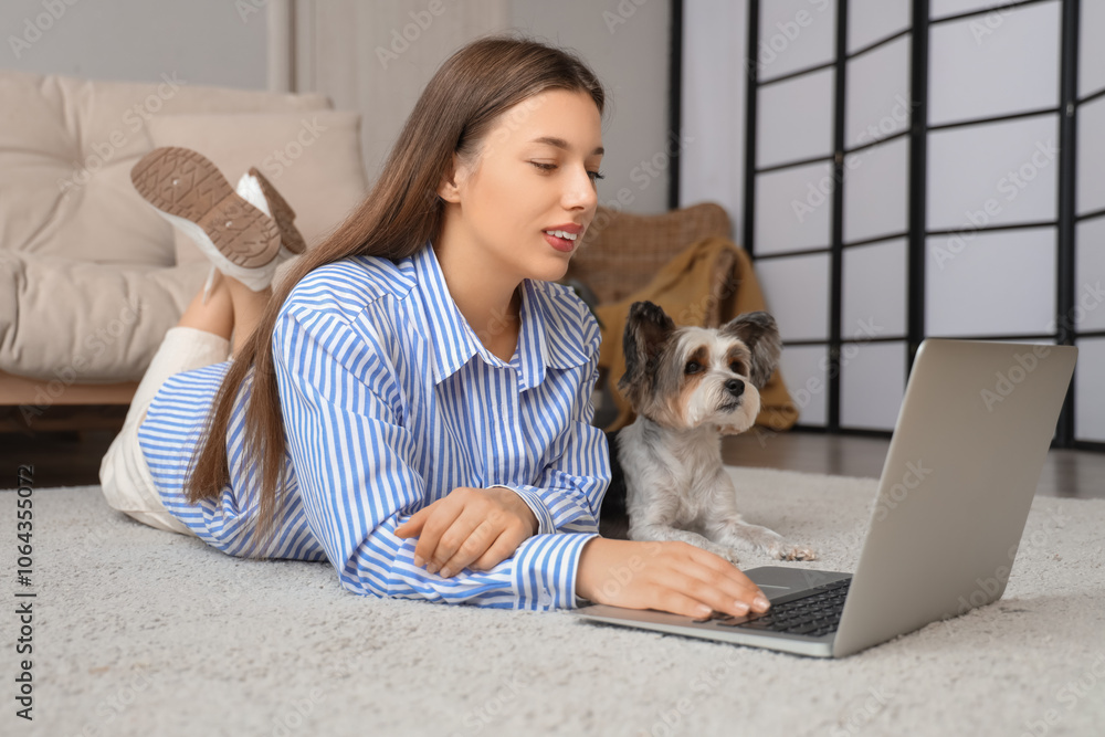 Young woman with cute Biewer Terrier dog using laptop on carpet at home Young woman with cute Biewer Terrier dog using laptop on carpet at home