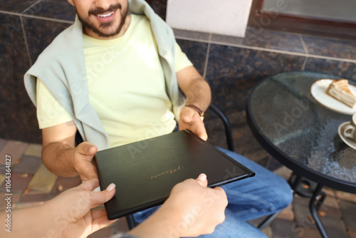 Young man taking menu from ...