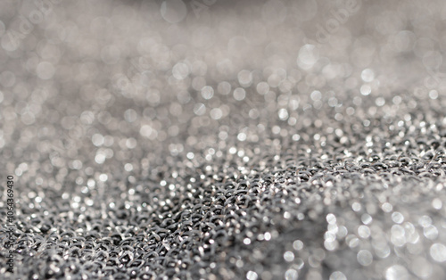 Vertical close-up of silver metallic mesh with blurs.