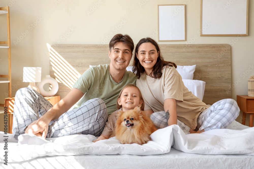 Happy little girl with her parents and Pomeranian dog sitting in bedroom Happy little girl with her parents and Pomeranian dog sitting in bedroom