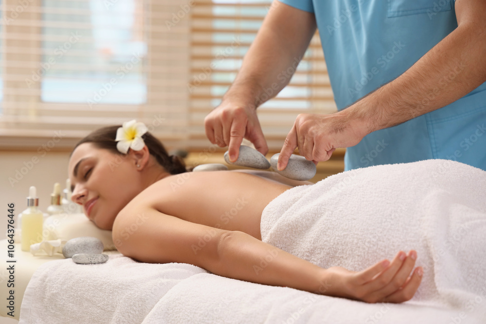 Young woman undergoing treatment with stones on couch in spa salon Young woman undergoing treatment with stones on couch in spa salon