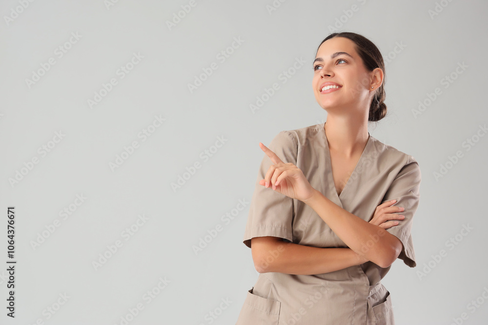 Female massage therapist pointing at something on light background Female massage therapist pointing at something on light background