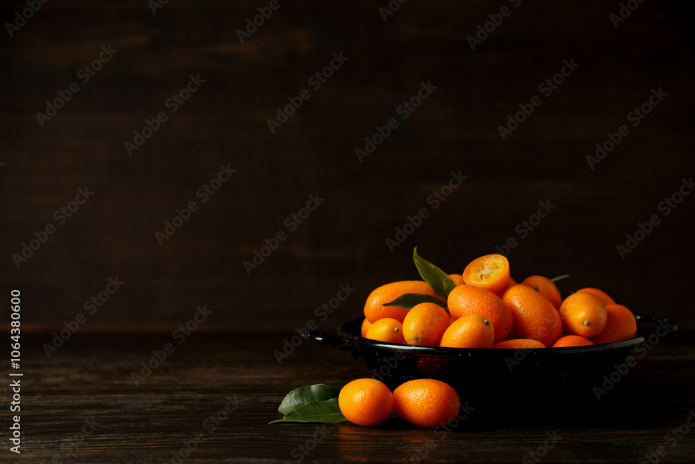 Naklejka premium Fresh kumquat fruits in pan on wooden background, space for text