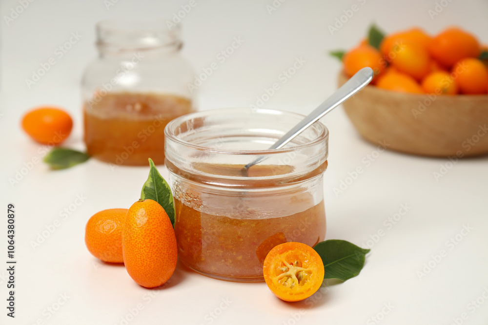 Kumquat fruits in bowl and glass jars with jam on white background Kumquat fruits in bowl and glass jars with jam on white background