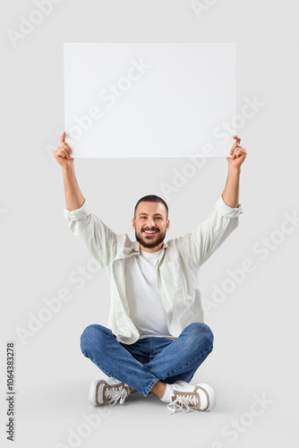 Young man with blank poster...