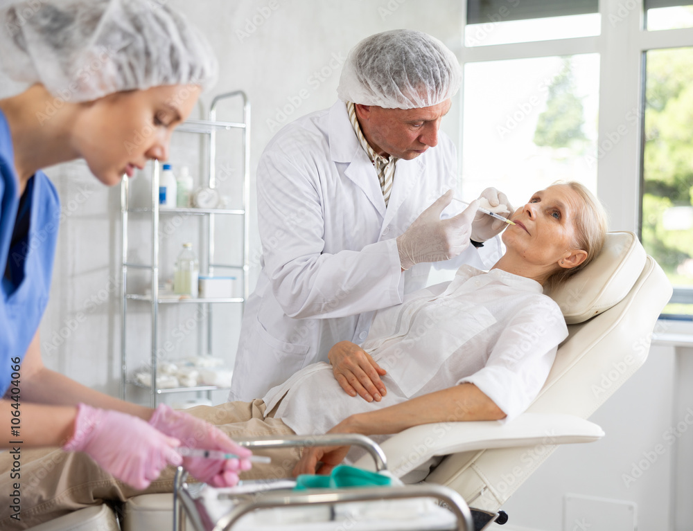 Φωτογραφία Professional cosmetic surgeon making face contouring injections to elderly female patient in cosmetology clinic, performing lip fillers