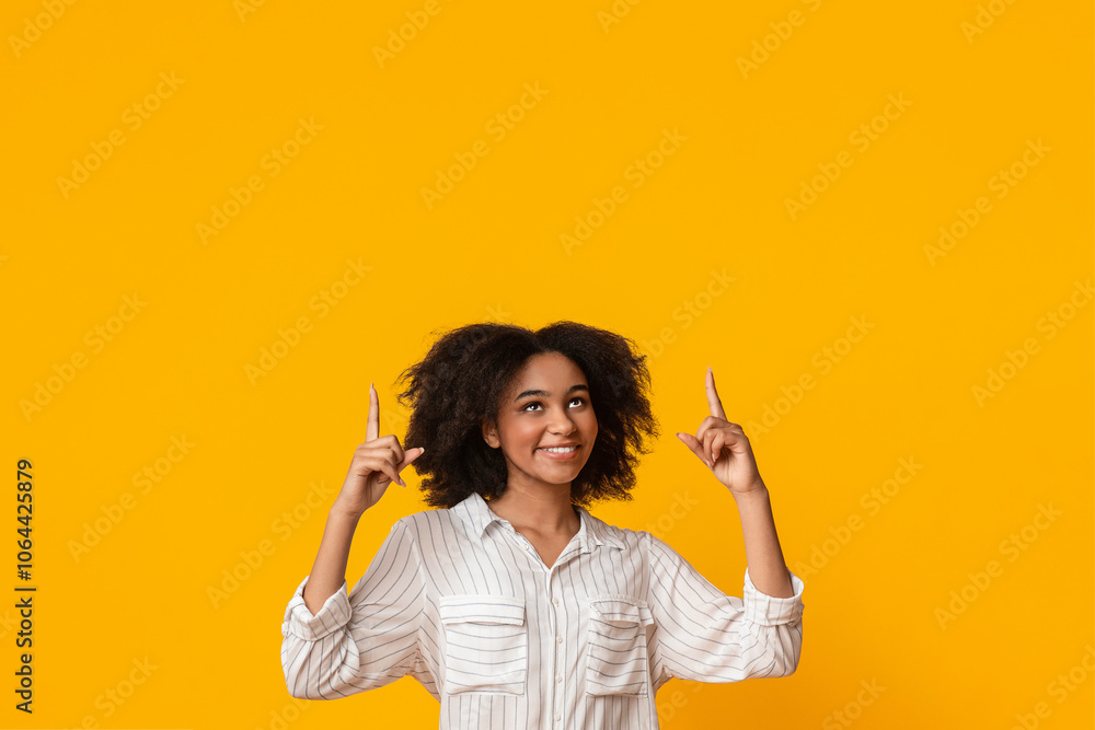 Look There. Happy Afro Girl With Funny Curls Pointing Upwards At Copy Space Above Her Head Over Yellow Background, Vertical Shot Look There. Happy Afro Girl With Funny Curls Pointing Upwards At Copy Space Above Her Head Over Yellow Background, Vertical Shot