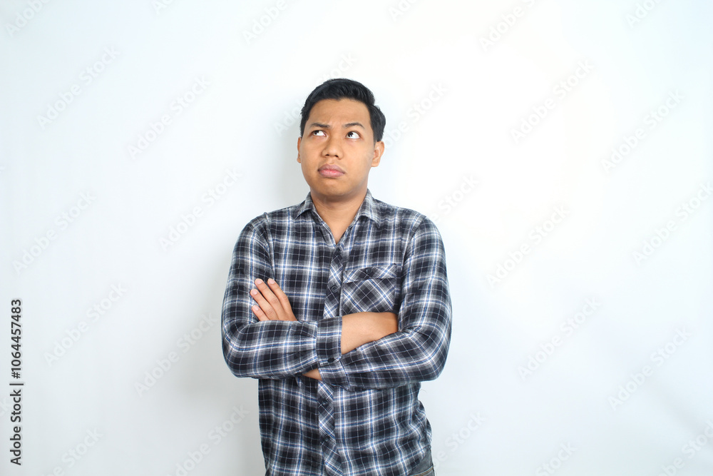 thoughtful asian man looking above with crossed hands wearing casual plaid shirt isolated on white background thoughtful asian man looking above with crossed hands wearing casual plaid shirt isolated on white background