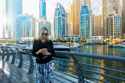 Happy beautiful tourist woman with smartphone enjoying vacation in Dubai in United Arab Emirates.