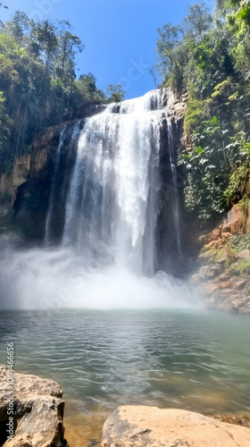 A cascading waterfall flows into a pool of water, surrounded by lush green foliage.