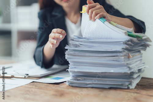 Tableau sur toile Overwhelmed with Paperwork: A woman sits at her desk, hands buried in a towering stack of documents, capturing the often overwhelming reality of office work