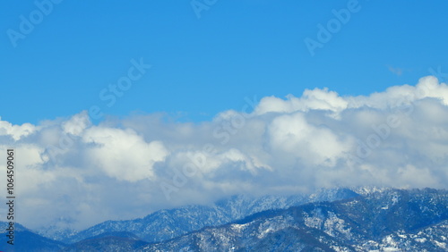 Beautiful Nature Of Mountain. White Clouds Quickly Float Over Snow-Capped Mountain Peaks Against Blue Sky. Timelapse.