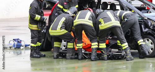 firefighters assisting the injured person with a stretcher after a car crash with a destroyed vehicle photo