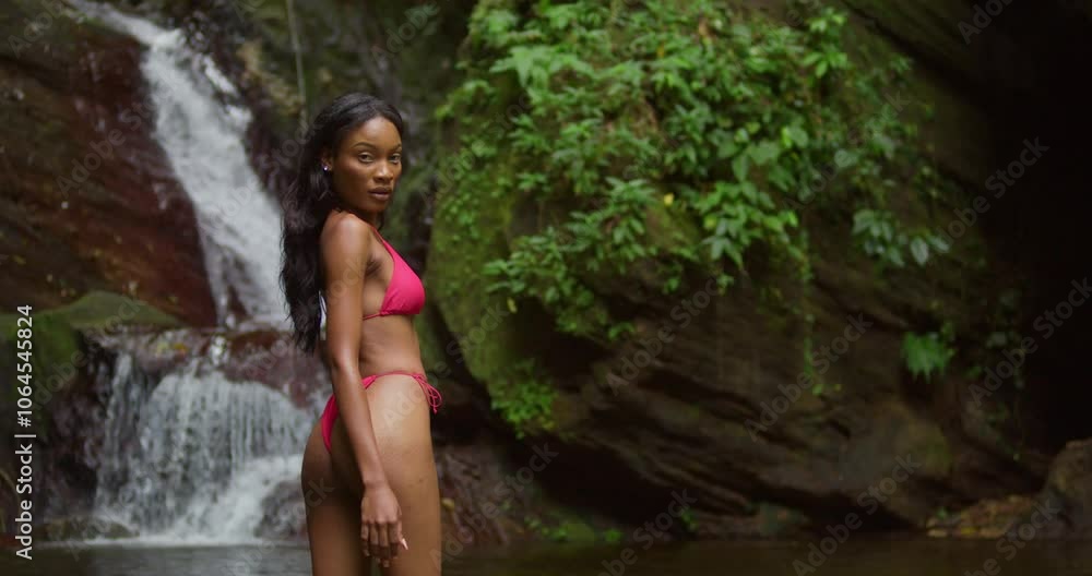 On the Caribbean island of Trinidad, a girl in a pink bikini finds peace by a cascading waterfall. On the Caribbean island of Trinidad, a girl in a pink bikini finds peace by a cascading waterfall.