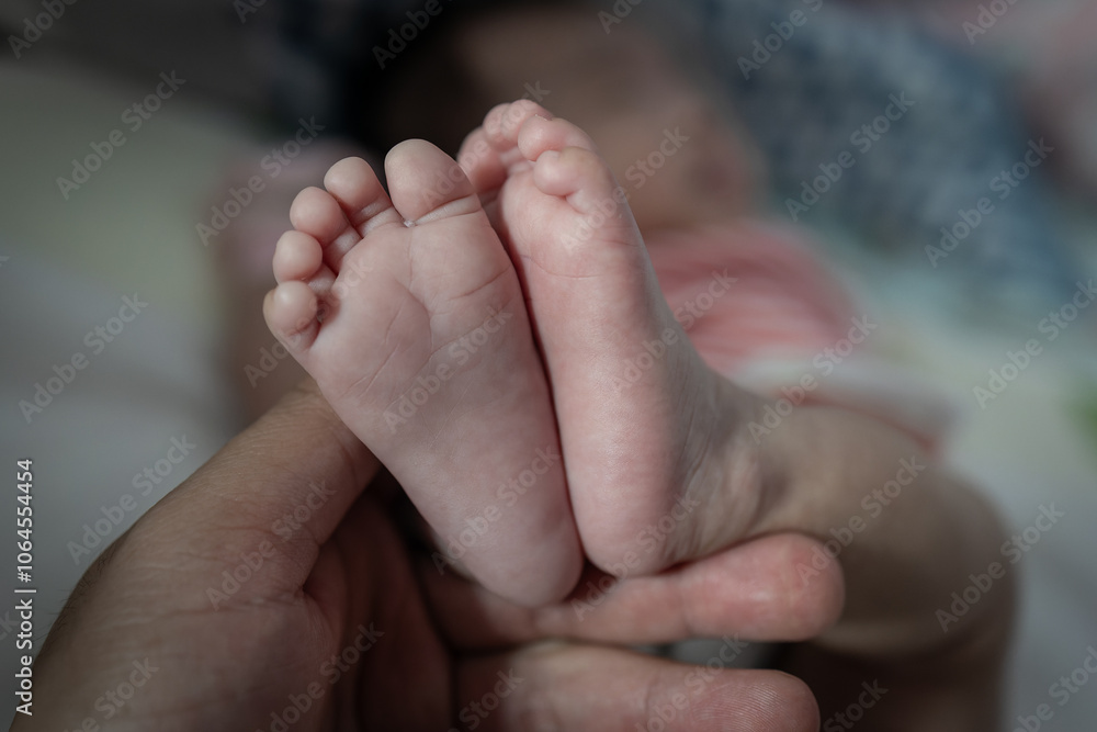 Father holding new born baby girl leg . father taking care of his daughter happy family dream of health Father holding new born baby girl leg . father taking care of his daughter happy family dream of health