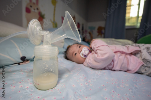 Asian Chinese mother using breast pump machine to pumping milk for her baby in bedroom. Colostrum milk, Transitional milk, Breast Pumping milk concept. photo